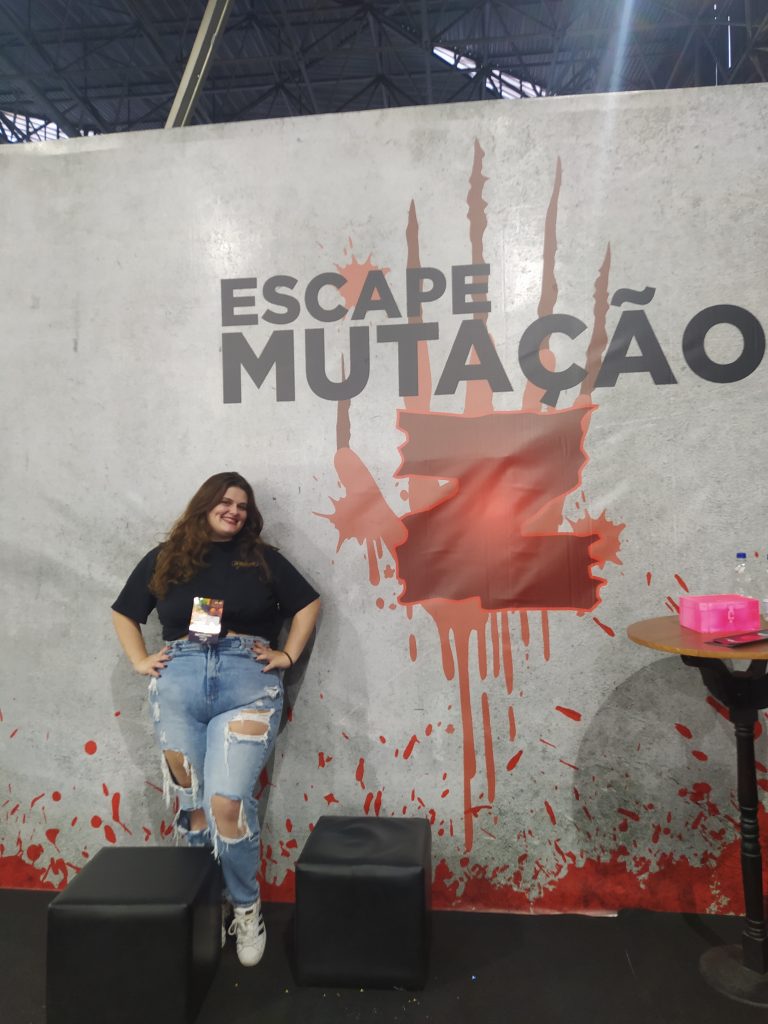 Letícia Ferrarez posa em frente ao cartaz da experiência imersiva do UCCONX
