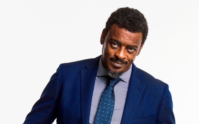 Seu Jorge em terno azul, posando para a foto