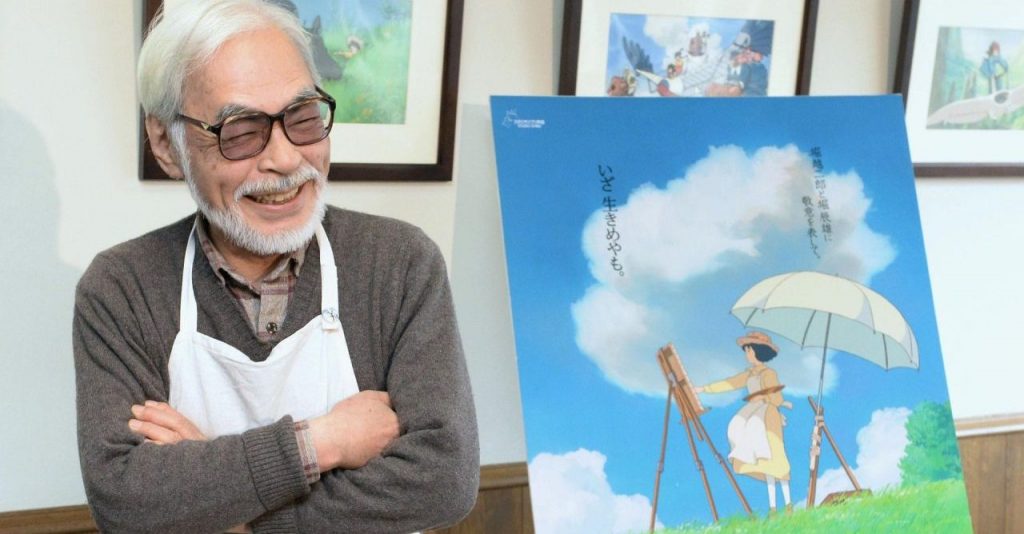 Hayao Miyazaki posa ao lado da pintura principal de Vidas ao Vento