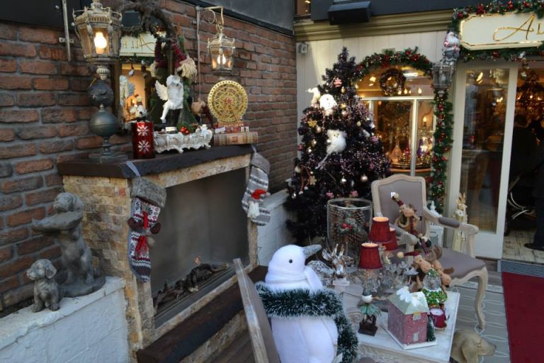 Vista diagonal de uma sala de jantar com decorações natalinas. Ao fundo, há uma árvore de Natal.