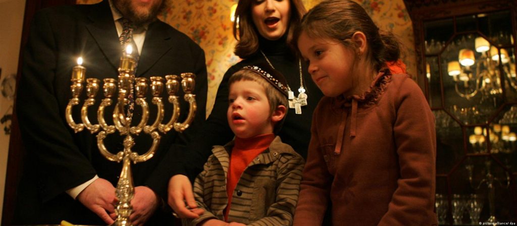 Família judaica observa um candelabro com oito velas.