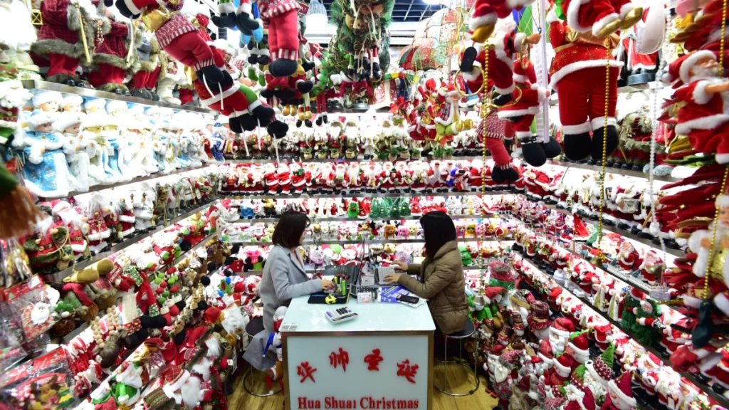 Duas mulheres chinesas estão no centro da imagem, rodeadas por decorações de Natal.