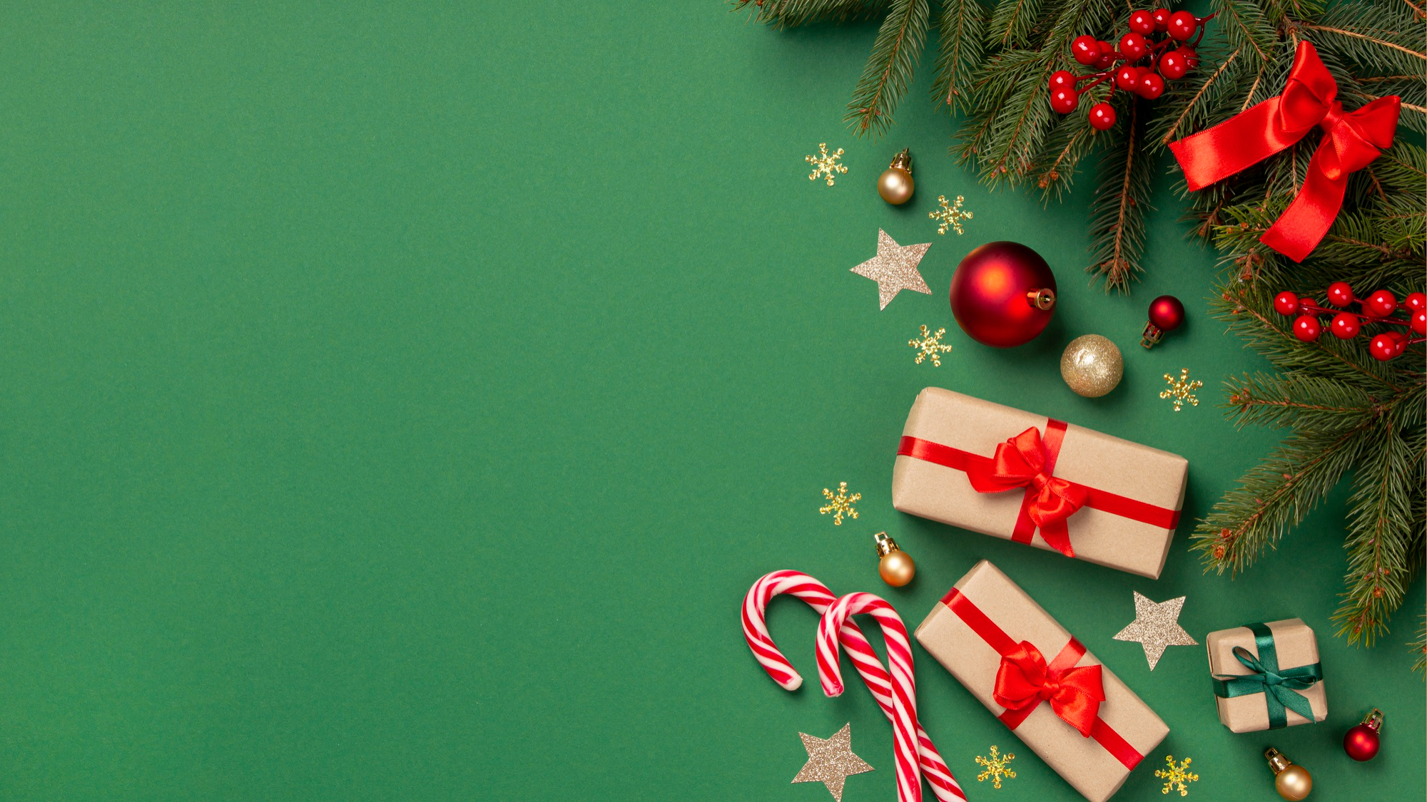 Símbolos do Natal, como bolas, caixa de presente, laços e guirlanda, espalhados por um fundo verde