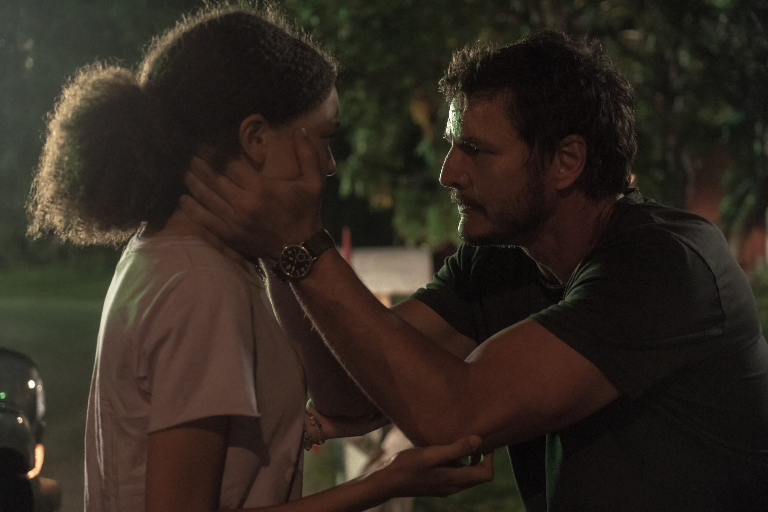 Pedro Pascal aparece abaixado, na altura dos olhos da atriz Bella Ramsey em cena do 1° episódio de The Last of Us.