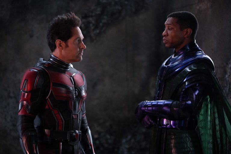 Paul Rudd, homem branco de cabelos pretos e curtos, como Scott Lang/Homem-Formiga e Jonathan Majors, homem negro de cabelos pretos e curtos, como Kang O Conquistador, em Homem-Formiga: Quantumania.