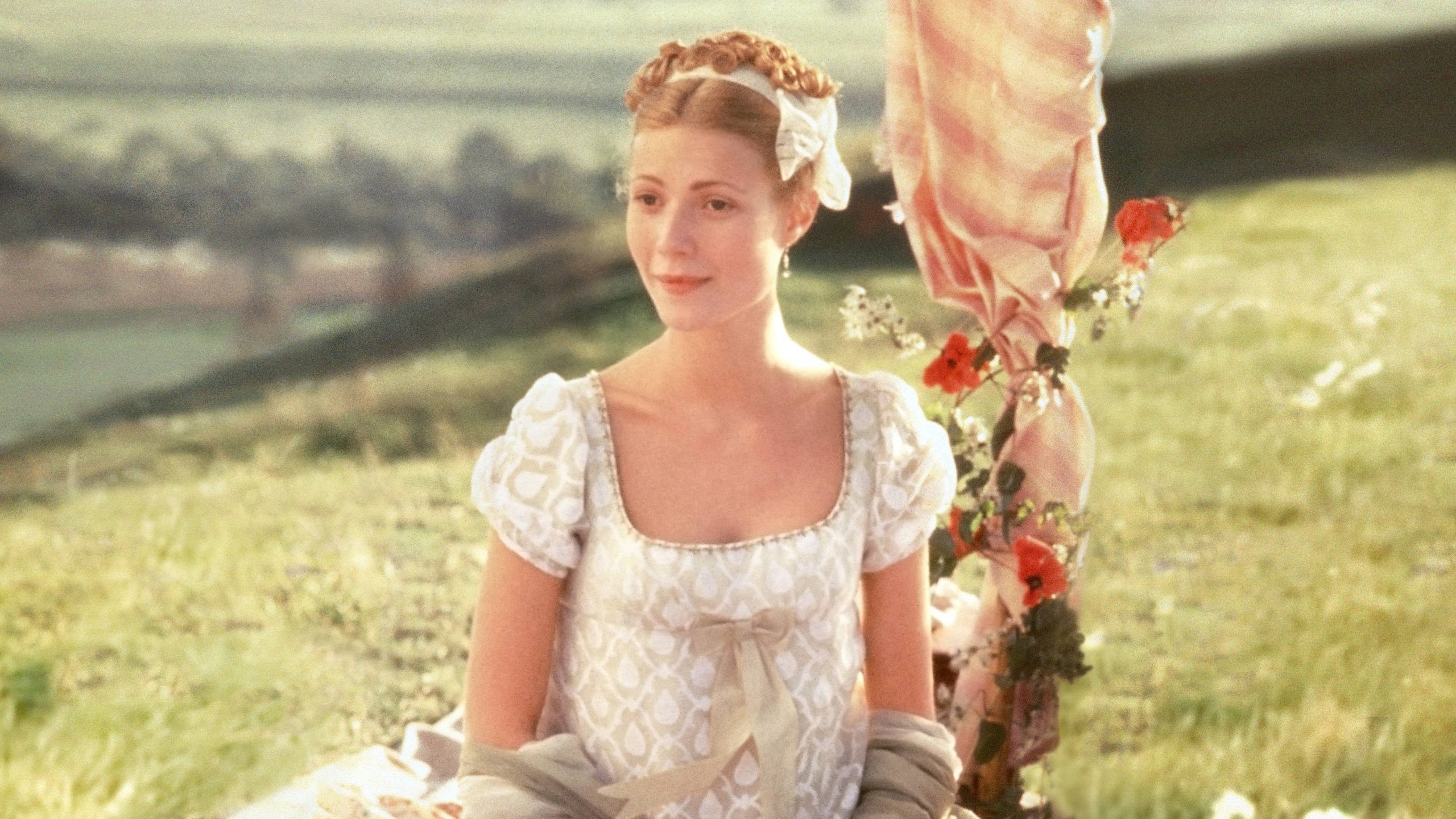 Frame de filme Emma, de Jane Austen. No frame em questão, a atriz Gwyneth Paltrow está no centro da imagem em meio a um campo verde