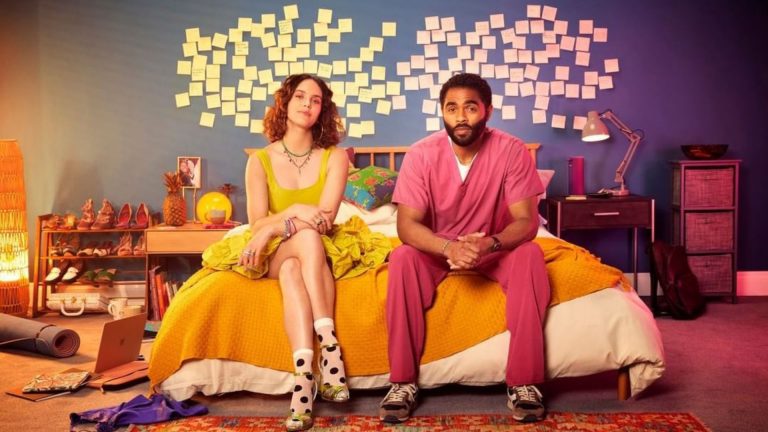 Uma mulher e um homem sentados no centro da cama com uma parede cheia de post-its